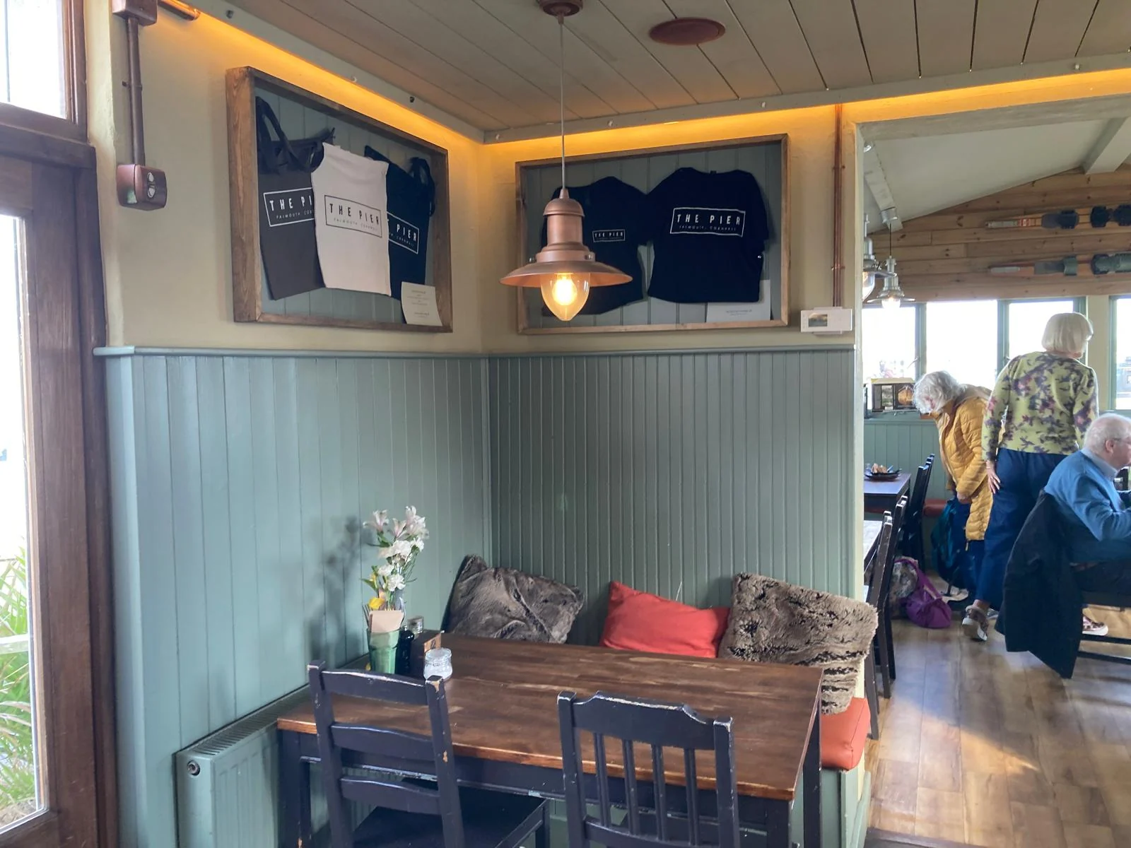 The green-panelled dining room at The Pier Cafe, with The Pier Falmouth branding displayed on the wall