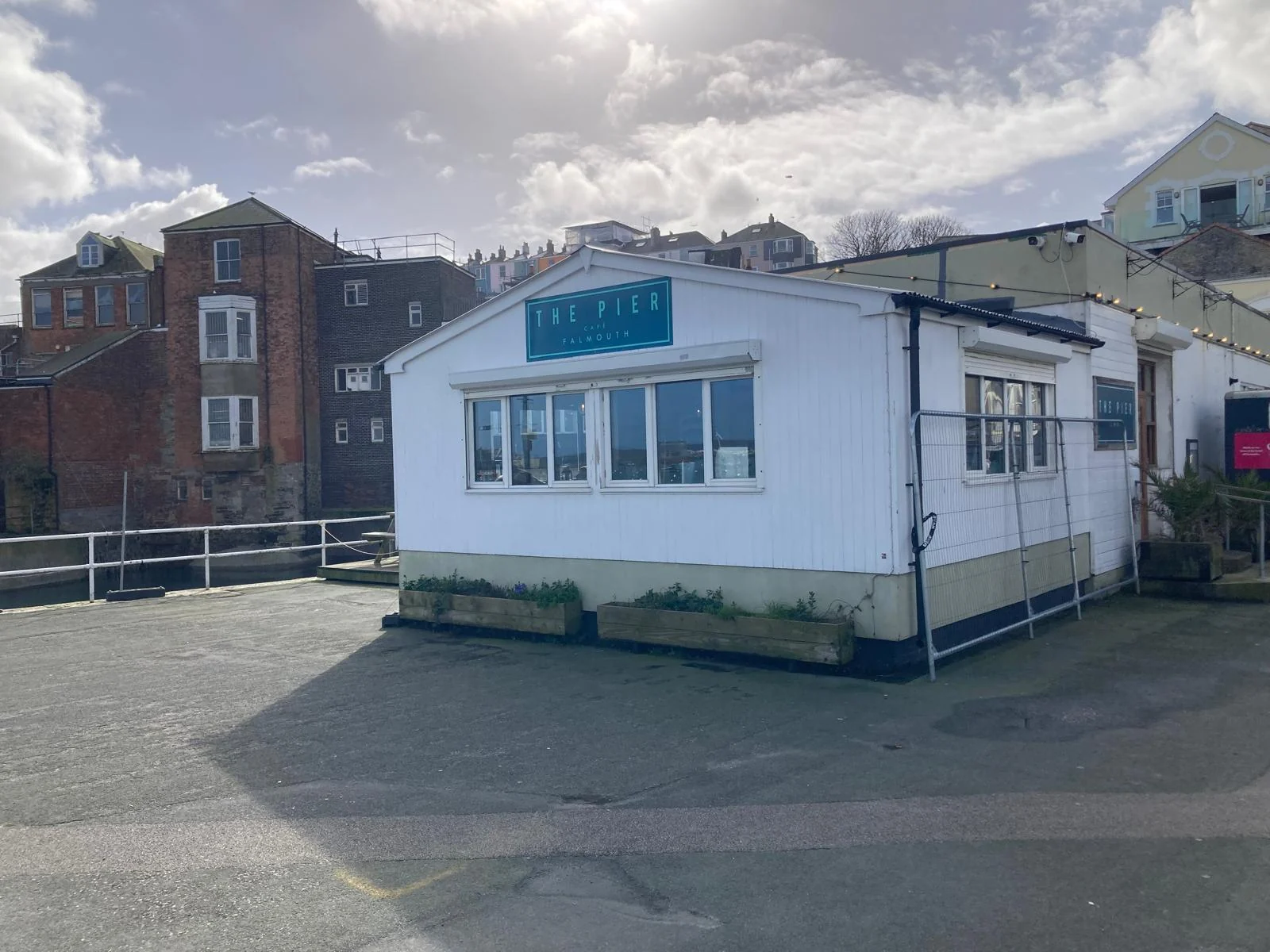 The real white cafe building on Prince of Wales Pier with The Pier Cafe Falmouth sign above the windows