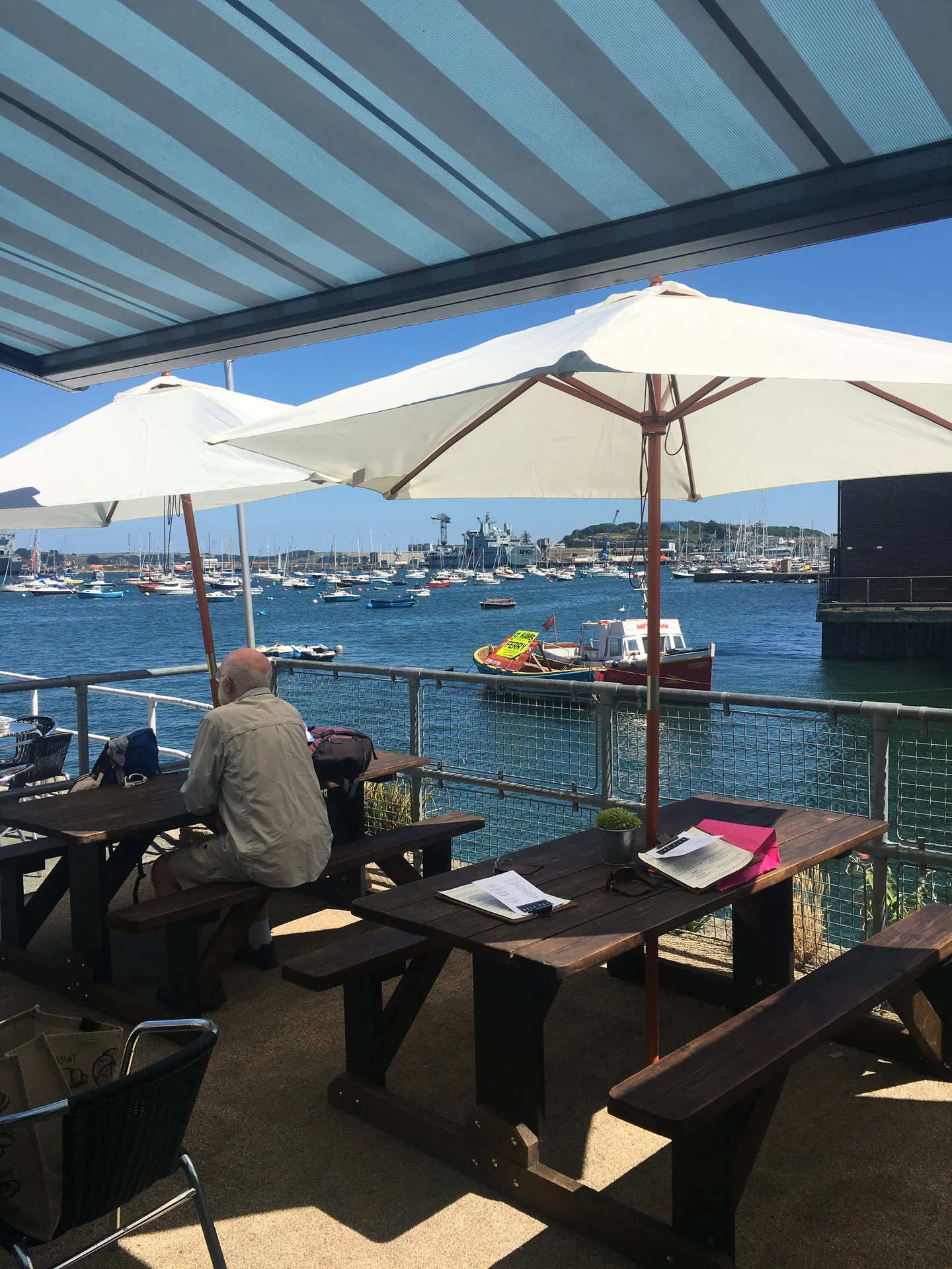 The Pier Cafe's outdoor tables and umbrellas overlooking Falmouth harbour